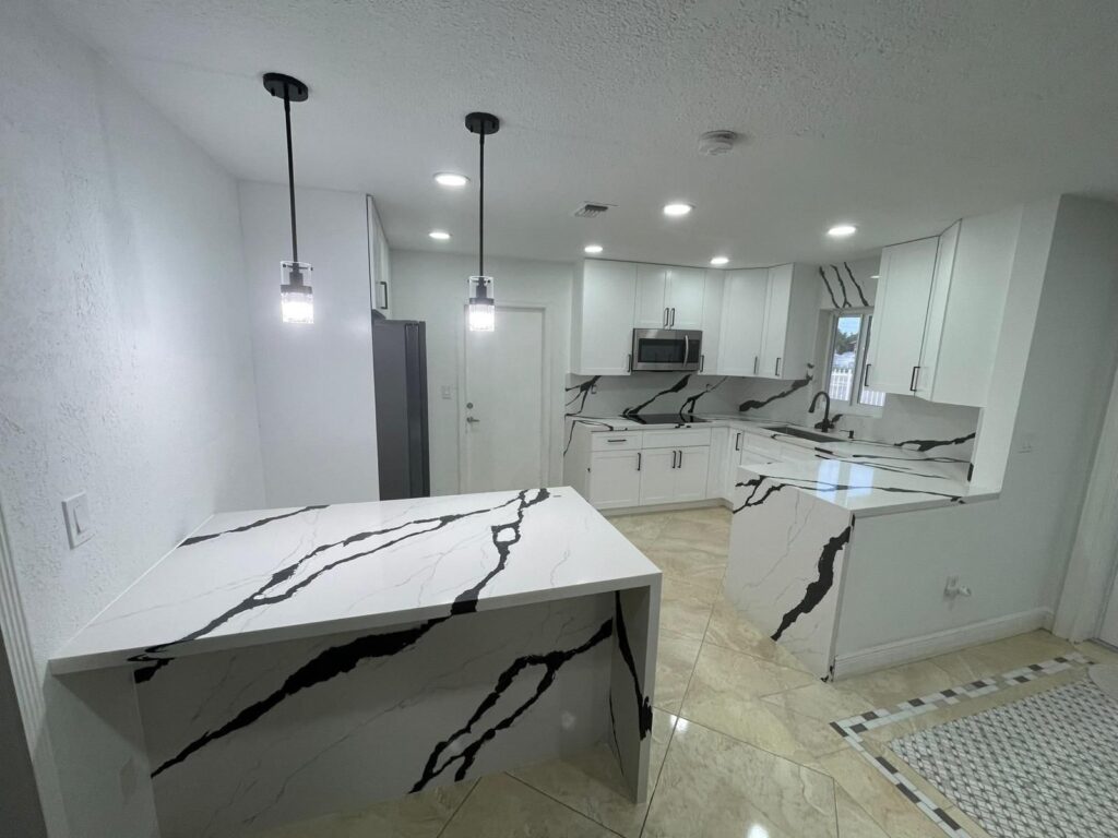 Modern kitchen with white cabinets and black marble-patterned countertops.
